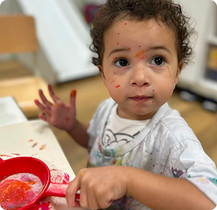 Criança brincando com tinta em atividade sensorial