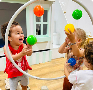 Crianças brincando com bambolê e bolinhas coloridas